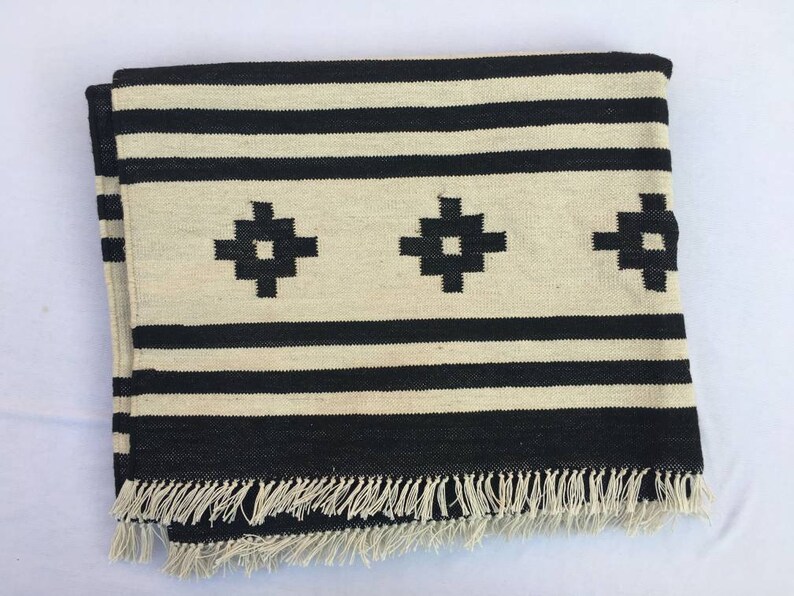 May include: Black and white striped throw blanket with a fringe border and three black geometric designs.