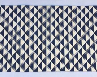 Puede incluir: Una alfombra geométrica con estampado blanco y azul marino con flecos en los bordes.