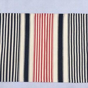 May include: A striped runner rug with alternating black and white stripes, and a red and white stripe in the centre.