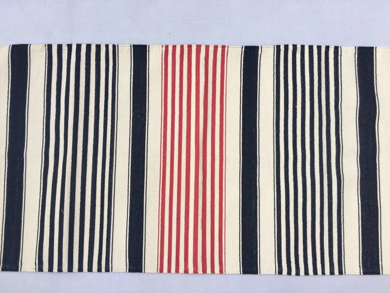 May include: A striped runner rug with alternating black and white stripes, and a red and white stripe in the centre.