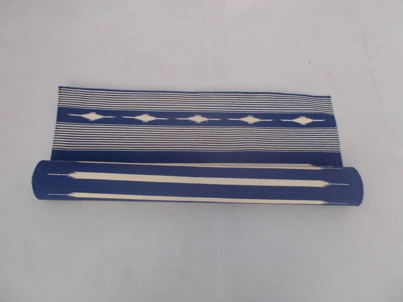 Peut inclure: Un tapis bleu et blanc ray&eacute; enroul&eacute; avec un motif g&eacute;om&eacute;trique. Le tapis est en coton et est parfait pour ajouter une touche de style &agrave; n'importe quelle pi&egrave;ce.