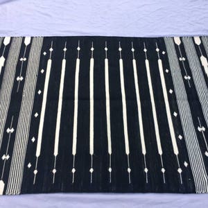 May include: Black and white striped rug with a geometric pattern. The rug has a fringe border.
