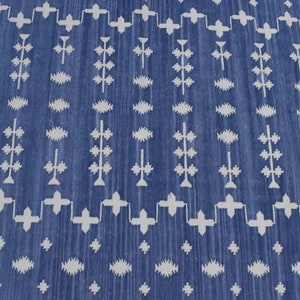 Puede incluir: Una alfombra azul y blanca con un dise&ntilde;o geom&eacute;trico. La alfombra tiene un patr&oacute;n repetitivo de cruces blancas, diamantes y l&iacute;neas verticales sobre un fondo azul.