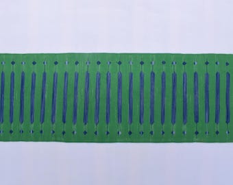 May include: A rectangular green rug with a repeating pattern of vertical blue lines and diamond shapes. The rug has cream-colored fringe on both ends. The rug is approximately 60 inches long.