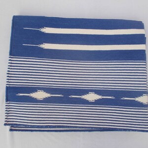 Peut inclure: Une couverture en laine ray&eacute;e bleu et blanc avec un motif g&eacute;om&eacute;trique. La couverture est tiss&eacute;e avec un fil &eacute;pais et textur&eacute;.