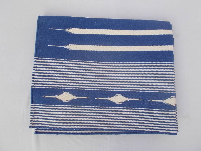 Peut inclure: Une couverture en laine ray&eacute;e bleu et blanc avec un motif g&eacute;om&eacute;trique. La couverture est tiss&eacute;e avec un fil &eacute;pais et textur&eacute;.