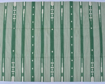 May include: A green and white striped rug with a geometric pattern. The rug has a fringed border.