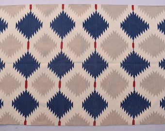 May include: A white rug with a geometric pattern of blue and red diamonds. The rug has a fringe border.