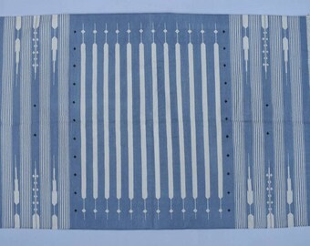 Puede incluir: Una alfombra de rayas azules y blancas con un patrón geométrico. La alfombra tiene un borde de flecos.