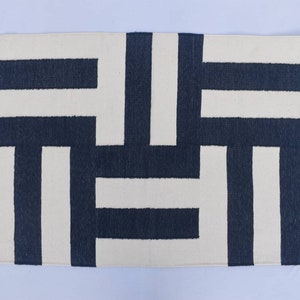 May include: A white and navy blue geometric patterned rug. The rug has a modern design with horizontal and vertical stripes.