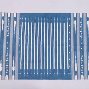 Peut inclure: Un tapis rayé bleu et blanc avec un motif géométrique. Le tapis a une bordure à franges.