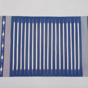 Peut inclure: Un tapis ray&eacute; bleu et blanc avec un motif g&eacute;om&eacute;trique aux extr&eacute;mit&eacute;s. Le tapis est fait d'un mat&eacute;riau tiss&eacute; et a une bordure frang&eacute;e.