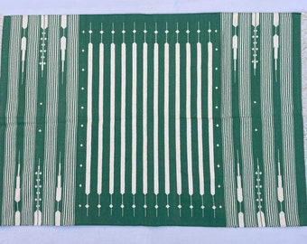 May include: A green and white striped rug with a geometric pattern. The rug has a fringed border.