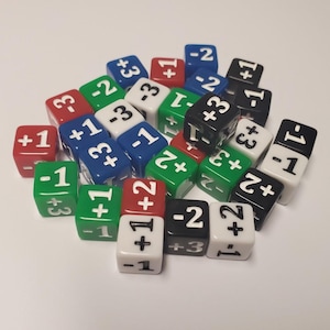 May include: A collection of 20-sided dice in various colors, including red, green, blue, black, and white. Each die has a different number printed on each side, ranging from -3 to +3.