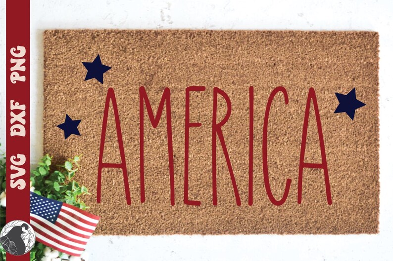 May include: A rectangular doormat with the word "AMERICA" in red, stylized letters. Three dark blue stars are placed around the word. An American flag and greenery are in the lower left corner.