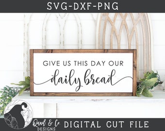 May include: A wooden sign with the text "GIVE US THIS DAY OUR daily bread" in a cursive font. The sign is brown with a white background and is sitting on a white shelf.