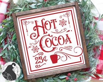 Puede incluir: Un letrero de madera rojo con letras blancas que dice "Hot Cocoa 25¢" con una taza de chocolate caliente estilizada y copos de nieve. El letrero está enmarcado en un marco de madera oscura.