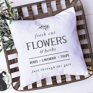 May include: White pillow with black text that reads "fresh cut FLOWERS & herbs ROSES ~ LAVENDER ~ TULIPS just through the gate". The pillow is sitting on a wooden crate.