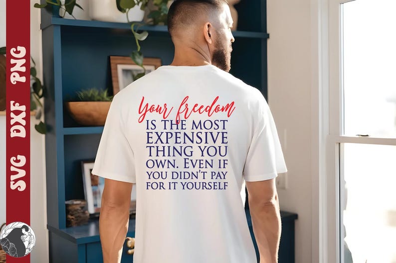 May include: A white t-shirt with the text "Your freedom is the most expensive thing you own. Even if you didn't pay for it yourself" in red and blue. The shirt is worn by a person.