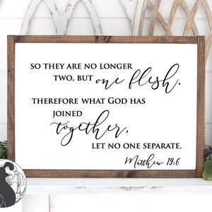 May include: A white wooden sign with a black inscription that reads "So they are no longer two, but one flesh. Therefore what God has joined together, let no one separate. Matthew 19:6".