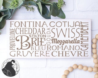 May include: A white wooden sign with the words "Fontina, Cotija, Cheddar, Swiss, Brie, Mozzarella, Bleu Romano, Gruyere, Chevre, Provolone, Stilton, Gouda, Camembert" written in brown text.