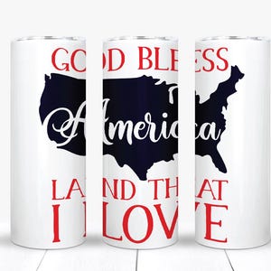 May include: White tumbler with a patriotic design. The design features a dark blue outline of the United States with the words "America" in a cursive font. The words "Good Bless" and "Land That I Love" are in red.