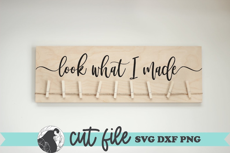 May include: A wooden sign with the text "look what I made" in black cursive script. The sign has a string with clothespins attached to it.