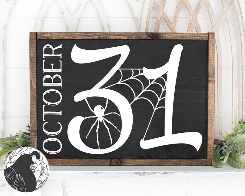 May include: A rectangular wooden sign with a black background and white lettering. The sign reads "OCTOBER" vertically on the left side and "31" with a spider web and spider design. The frame is a dark brown color.
