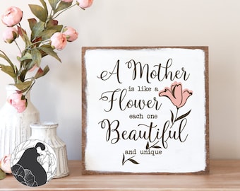 May include: A white wooden sign with brown text that reads "A Mother is like a Flower each one Beautiful and unique". A pink flower is illustrated on the sign.