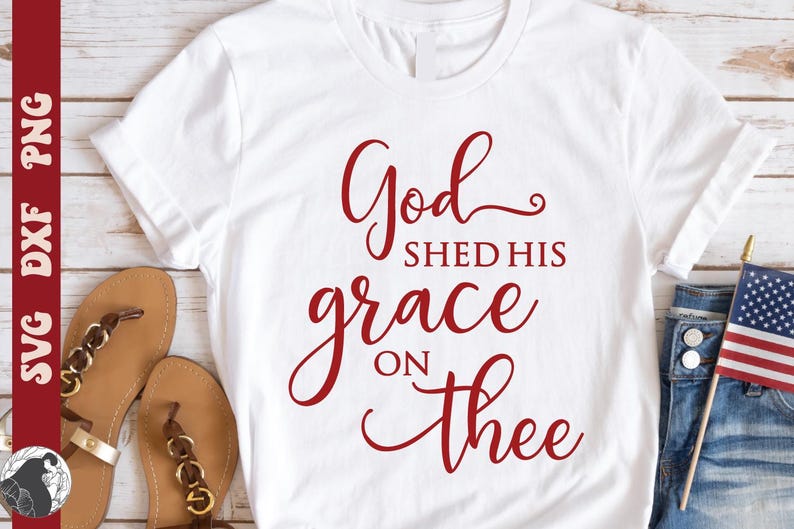 May include: White t-shirt with the red text "God shed his grace on thee." The shirt is paired with brown sandals, blue jeans, and a small American flag. The design is suitable for patriotic or religious themes.