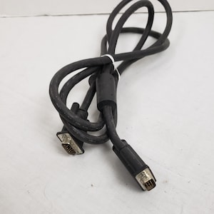 May include: A black computer cable with two connectors. The cable is coiled and secured with a white tie. The connectors have metal pins and are designed to connect to a computer or other electronic device.