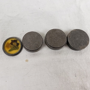 Puede incluir: Cuatro cajas redondas para joyas de color plateado con un diseño floral. Una caja tiene una tapa transparente con una flor prensada en su interior.