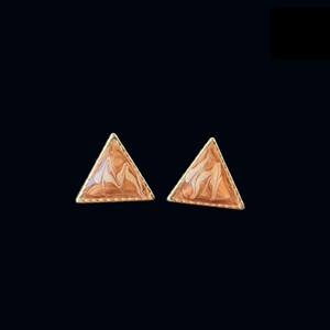 May include: A pair of triangular earrings with a gold-colored border. The earrings have a marbled pattern in shades of brown and cream. The earrings are set against a black background.