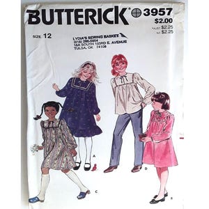 May include: A vintage Butterick sewing pattern envelope, size 12, featuring illustrations of children's clothing designs. The envelope includes the text "BUTTERICK 3957" and the store name "LYDIA'S SEWING BASKET". The designs include dresses and blouses.