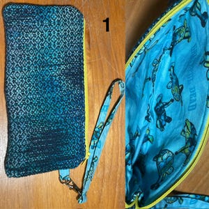 May include: A blue and teal woven clutch with a yellow zipper. The interior features a blue fabric with a turtle pattern. A matching wrist strap is attached. The clutch is on a wooden surface.
