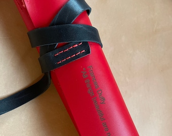 May include: A red leather roll with a black leather strap and the quote "All things beautiful are never perfect" by Frances Duffy.