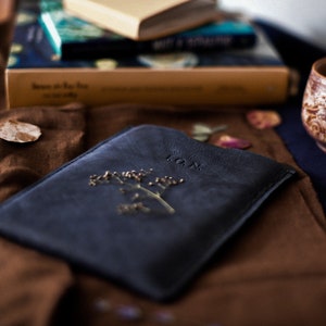 May include: A dark blue leather journal with a pressed flower and the word "LOAN" embossed on the cover.