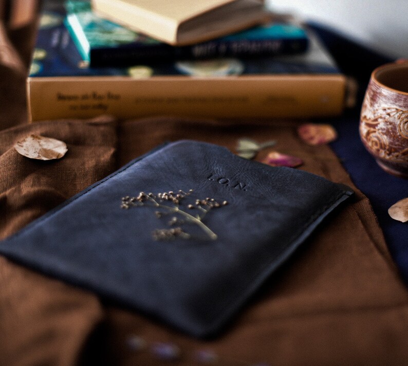 May include: A dark blue leather journal with a pressed flower and the word "LOAN" embossed on the cover.
