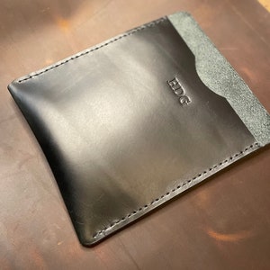 May include: Black leather card holder with a stitched edge and the word "EDG" embossed on the front.