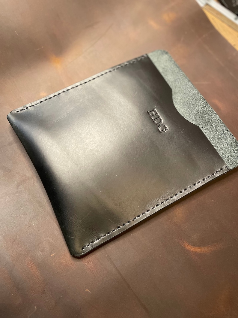 May include: Black leather card holder with a stitched edge and the word "EDG" embossed on the front.