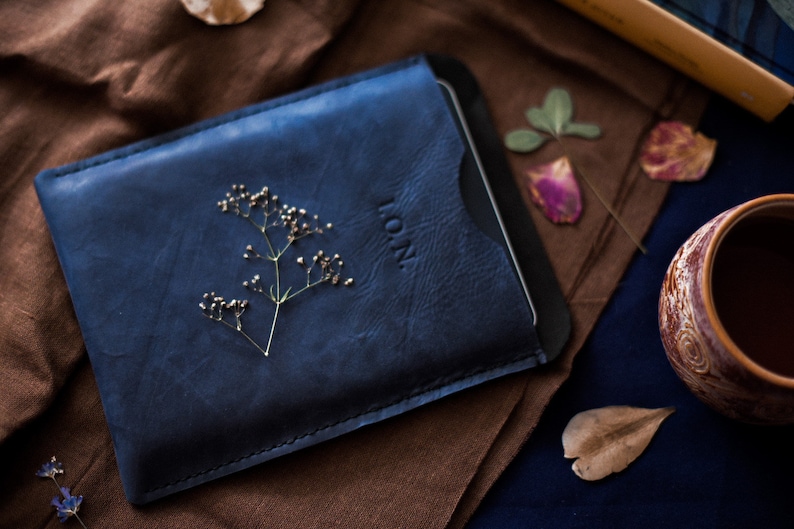 May include: A blue leather case with a small sprig of dried flowers and the word "L.O.N." embossed on the front.