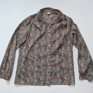 May include: A long-sleeved paisley patterned shirt with a button-up front and a collared neckline. The shirt is in shades of brown, green, and cream.