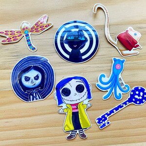 Puede incluir: Un conjunto de diez pegatinas coloridas con varios personajes y dise&ntilde;os. Las pegatinas incluyen un gato negro con un dise&ntilde;o de espiral blanco, un pulpo azul, una llave con una estrella azul, una ni&ntilde;a con cabello azul, una ni&ntilde;a con cabello negro, una lib&eacute;lula y un rat&oacute;n blanco con ropa roja.