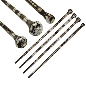 May include: Five intricately carved walking sticks with decorative inlays of white and gold. The sticks have a dark brown finish and feature a rounded knob at the top.