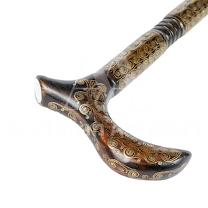 May include: A wooden walking stick with a decorative handle. The handle is shaped like a crescent moon and is decorated with intricate gold swirls. The stick is made of dark wood and has a polished finish.