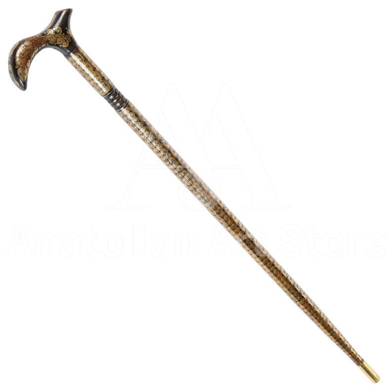 May include: A decorative walking stick with a gold and black patterned design. The handle is curved and has a gold finish.