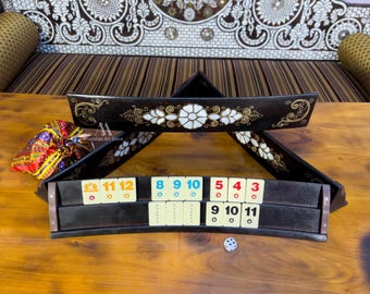 Puede incluir: Un juego de backgammon de madera con un diseño triangular. El juego está decorado con incrustaciones de nácar y detalles dorados. El juego incluye una bandeja con un borde elevado y un juego de dados.