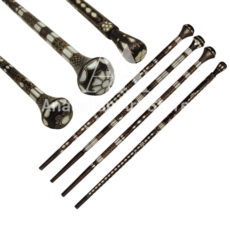May include: Five intricately carved walking sticks with decorative inlays of white and gold. The sticks have a dark brown finish and feature a rounded knob at the top.