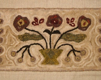 Könnte beinhalten: Ein handgefertigter Teppich mit einem floralen Muster. Der Teppich zeigt drei braune Blumen mit gelben Zentren, grünen Blättern und braunen Stielen. Die Blumen sind in einer Vase mit einem grün-braunen Muster angeordnet. Der Teppich ist von einem weißen Rand umgeben.
