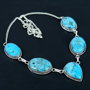 Op de afbeelding: Een turquoise halssnoer met vijf ovale en druppelvormige stenen gezet in zilver. De ketting heeft een zilveren ketting.